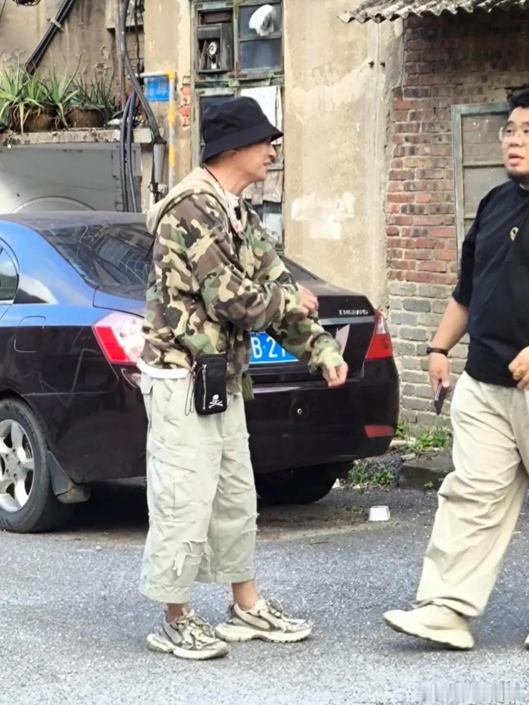 65岁吴镇宇在广西柳州一处旧小区游玩被偶遇，他的穿衣打扮个性十足，他身穿迷彩服配