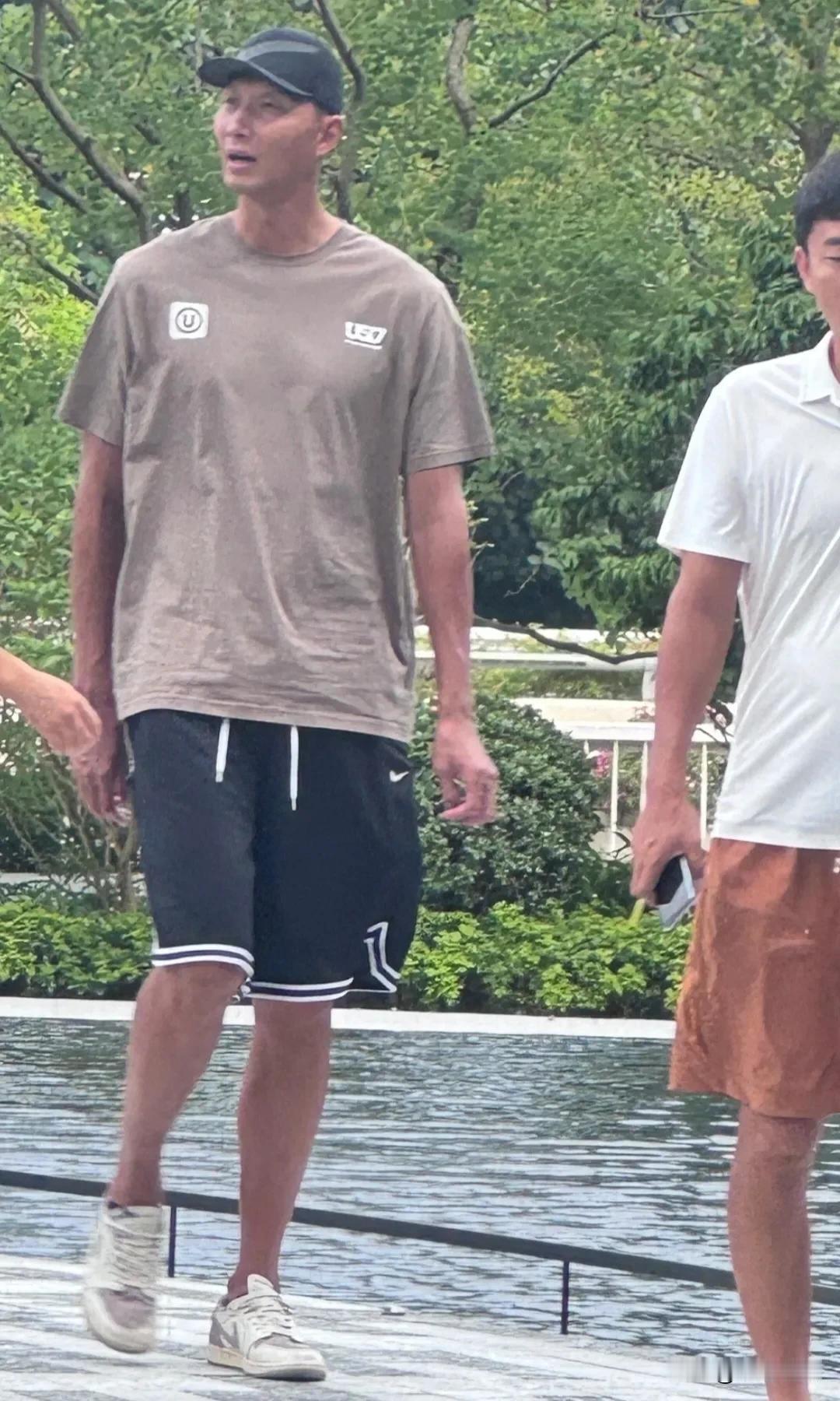 篮球运动员易建联现身广东。他个子超高，肤色很黑，戴着棒球帽穿着T恤运动短裤。感