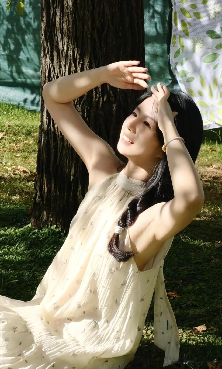 阳光洒落，树影婆娑，少女轻倚树干，笑靥如花。