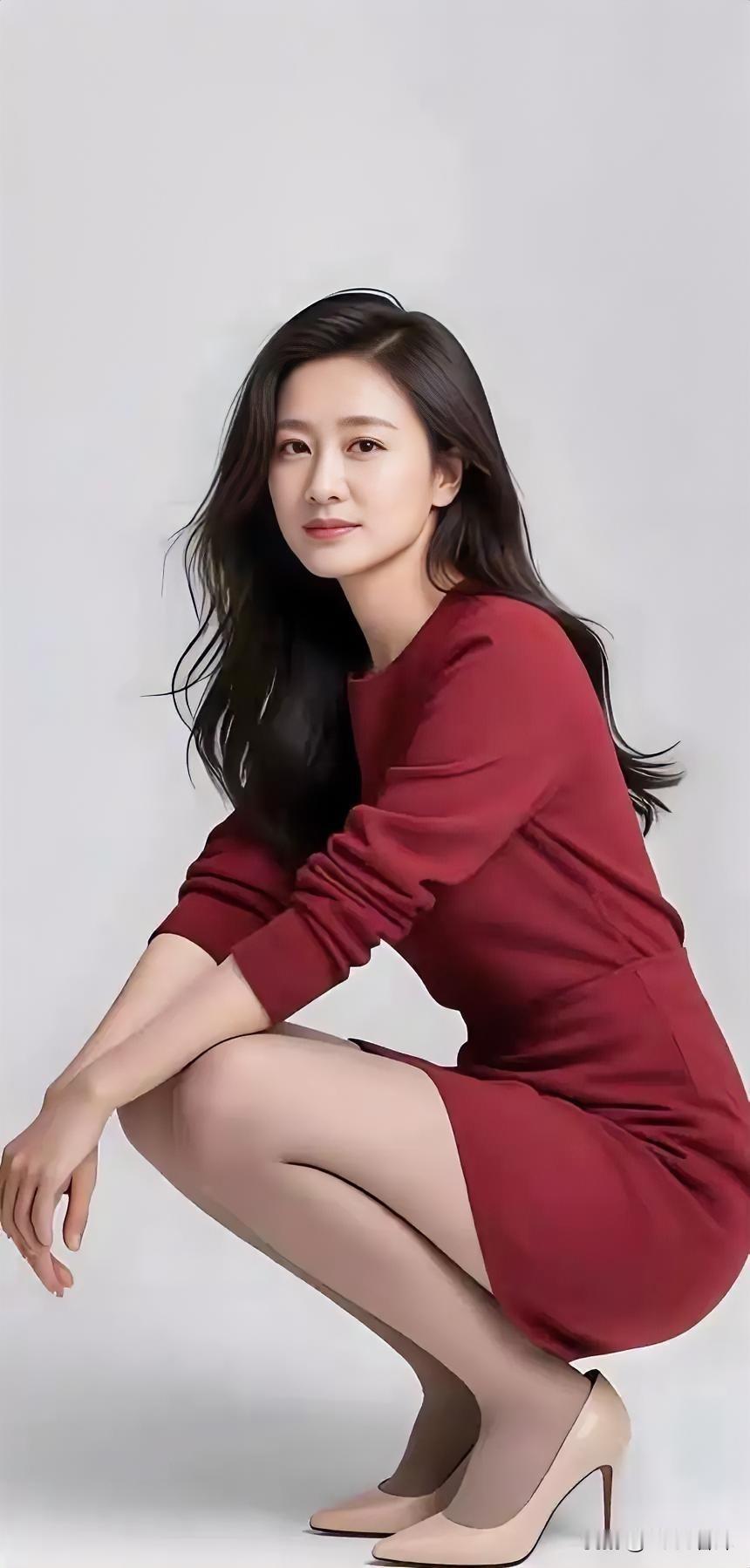 红裙曳光影，蹲姿绽从容。黑发随心动，高跟叩静空。素白为背景，美在简中浓。