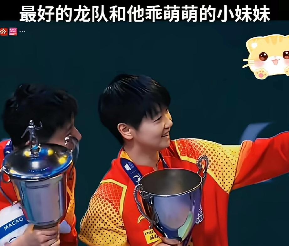 龙队和乖萌萌莎莎合影！莎莎看着身边的龙队，高兴的拿着手机拍照，小虎牙都笑出来了