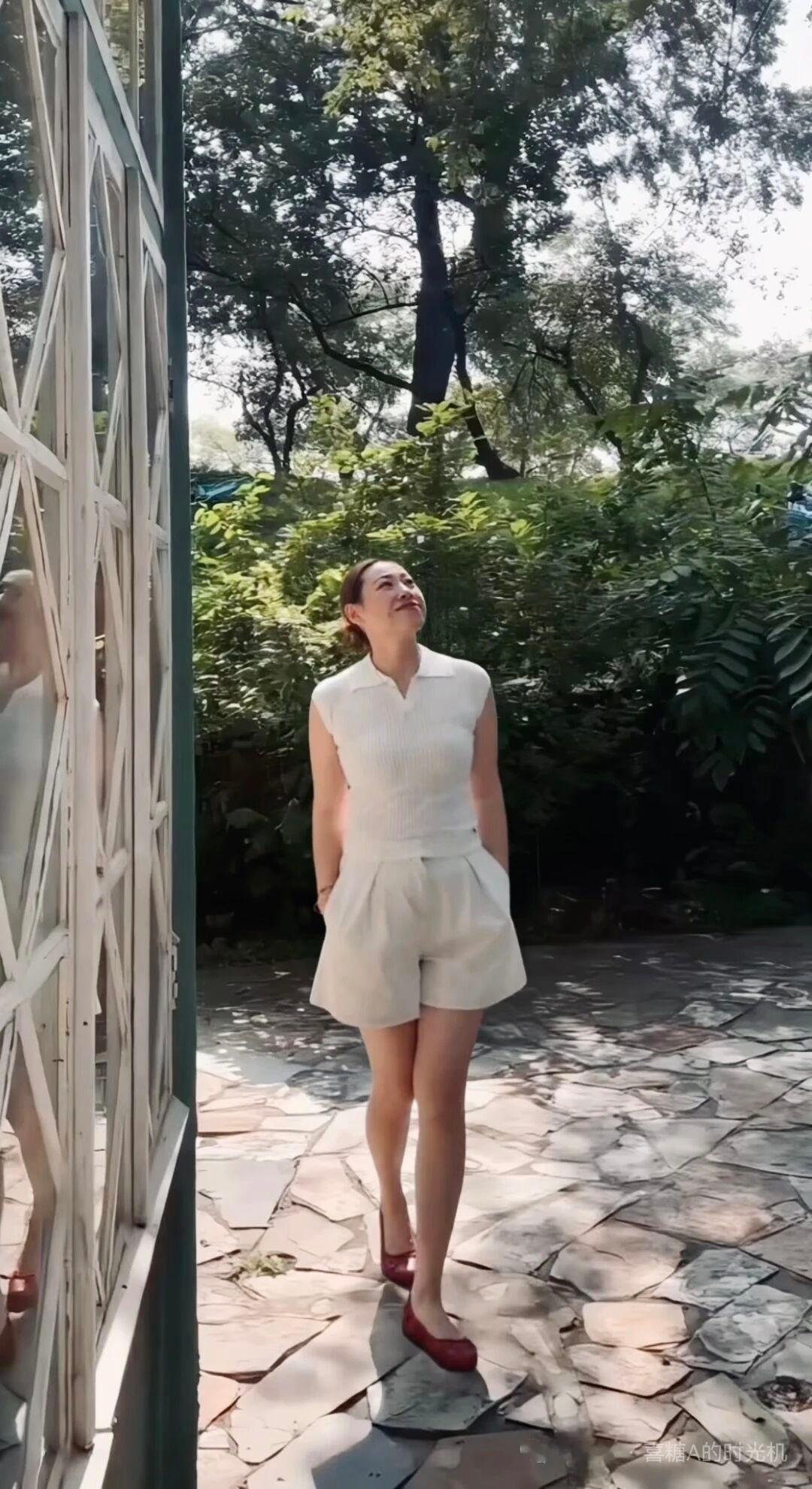 阳光明媚，她在树荫下微笑。