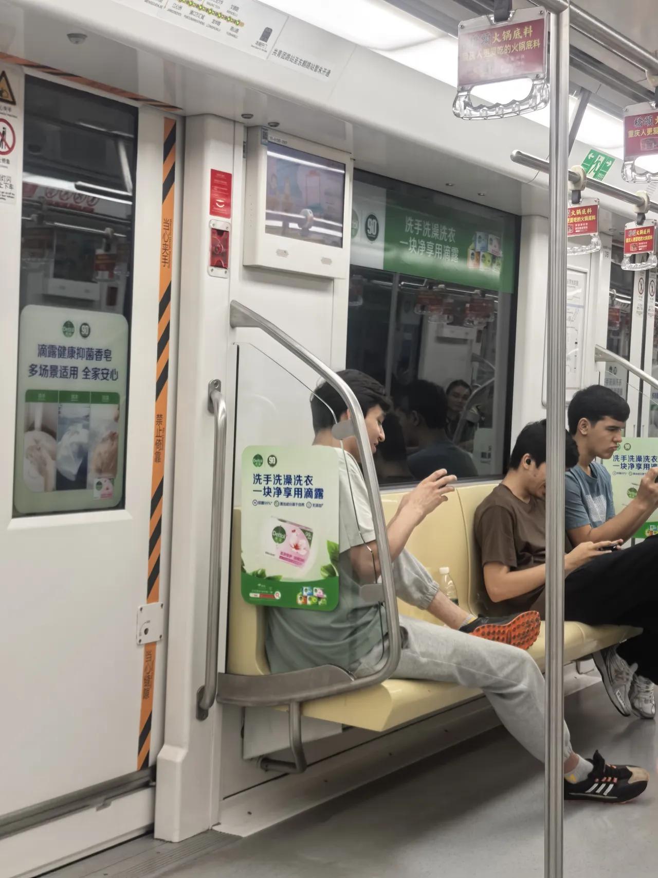 这是南京地铁10号线。几位外籍留学生（看不出来哪个国家），坐在座位上看手机，一
