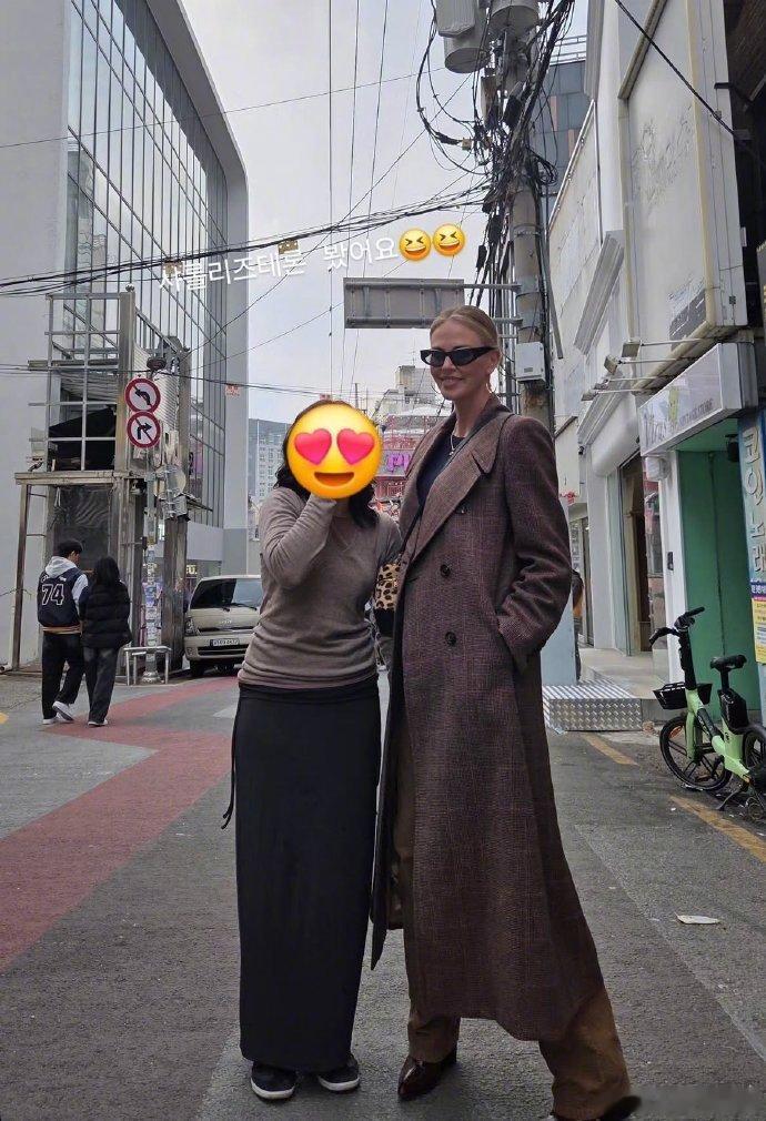 23日，网友在首尔弘大街道偶遇好莱坞演员查理兹・塞隆与女儿一同游玩，塞隆身着棕色