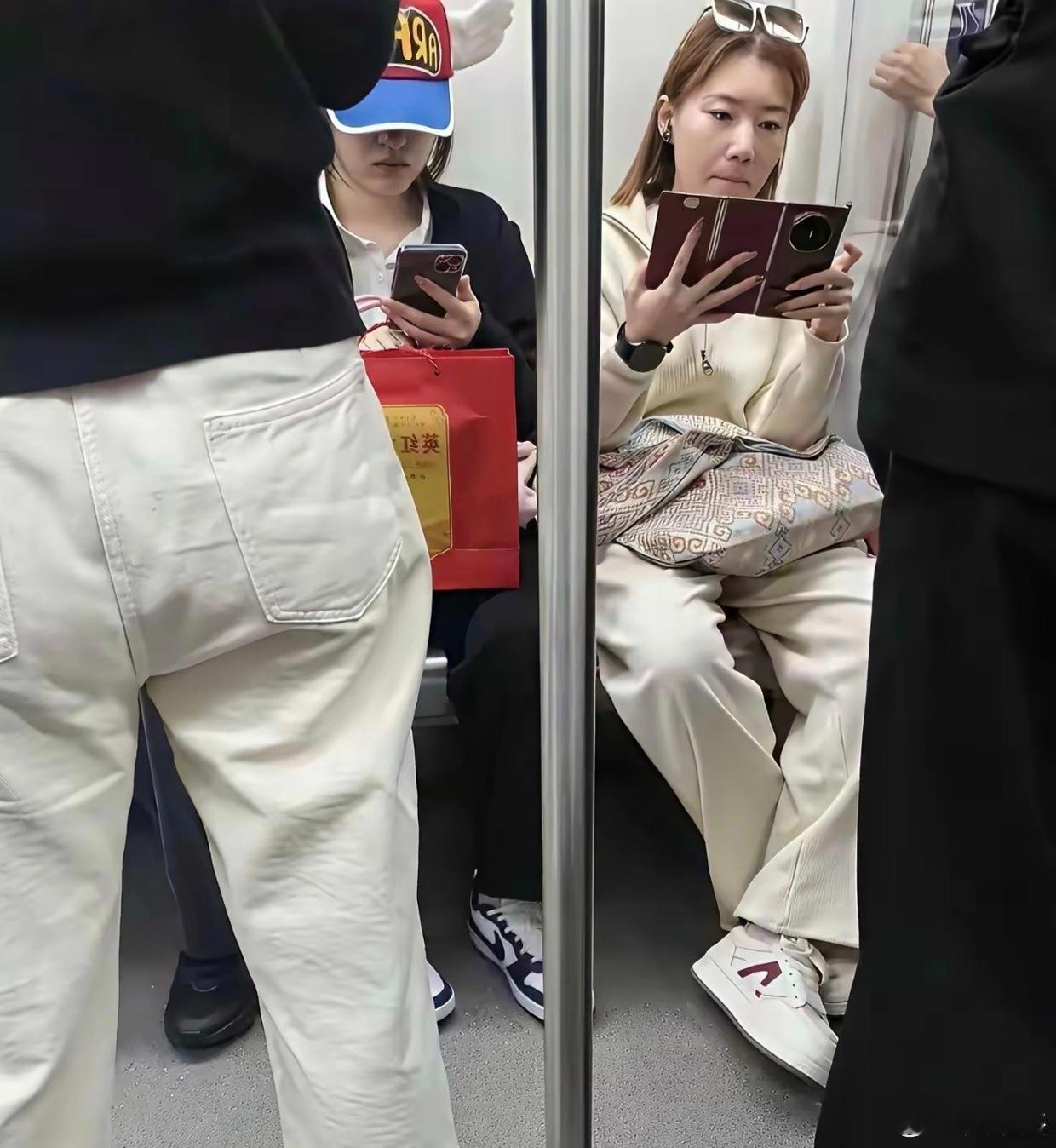 地铁上一个打电话，一个看三折叠手机，哪个是摆拍？