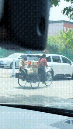山东街头，妈妈蹬三轮卖粽子，一回头，车斗里的孩子正在写作业，这一幕，拍得毫无技巧