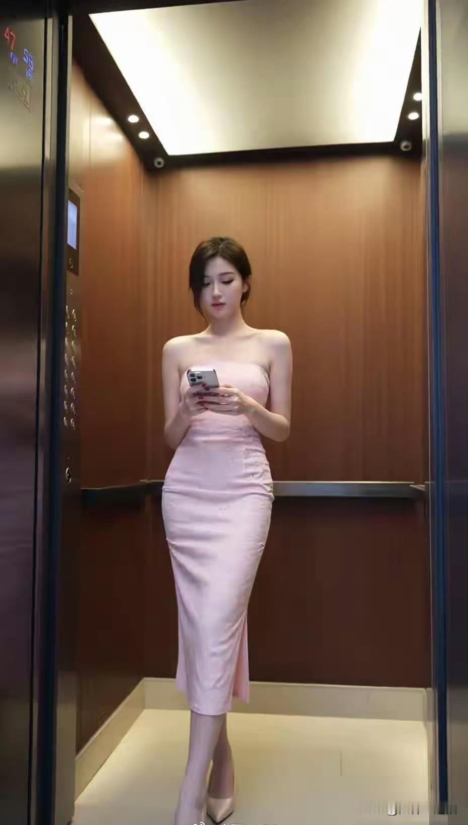 优雅电梯女神，粉色裙摆飘逸，手机轻触间尽显时尚魅力。