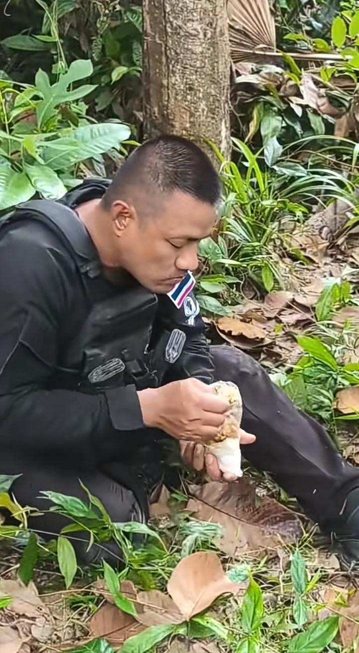 泰国的一名士兵在野外吃午饭，用塑料袋装的米饭和菜，他却吃的非常认真，如果他的父母