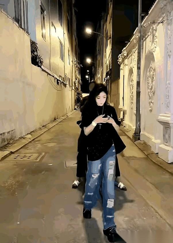 马路不宽，一个姑娘，低着头，正对着手机屏幕全神贯注。脚步很慢，走得歪歪扭扭，像