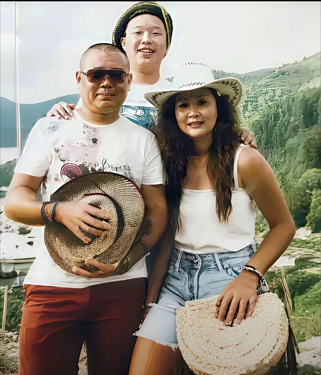 相声演员郭德纲早年带着老婆和儿子，一家三口去旅游的照片。郭德纲戴着遮阳镜，手里拿