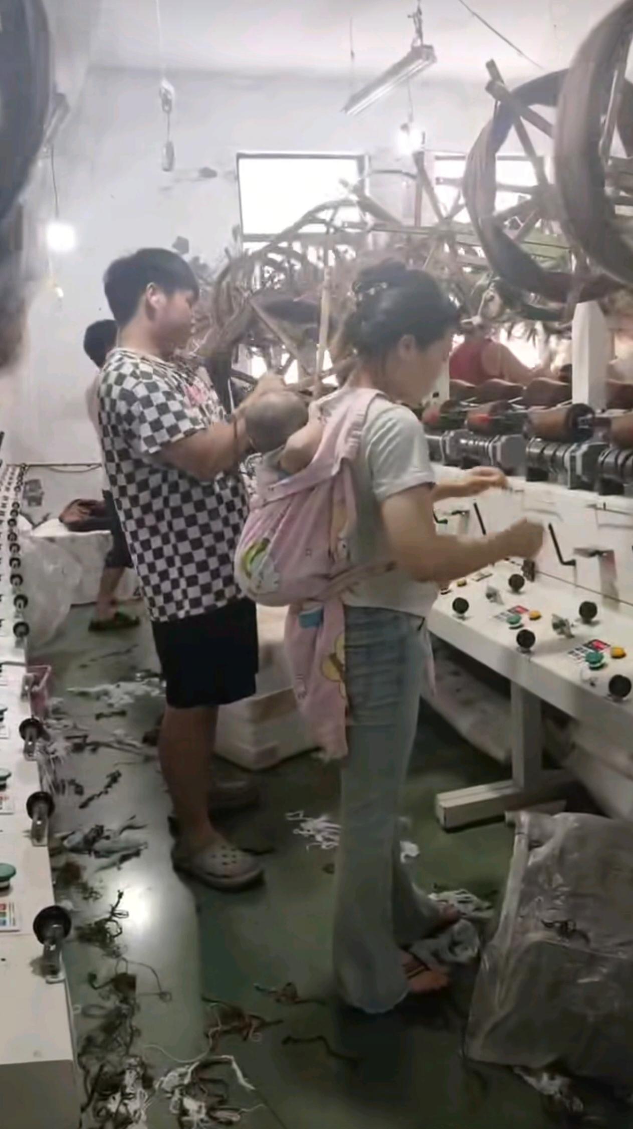 工厂车间里，这位妈妈把小宝宝背在身后干活。孩子就这么被绑缚一整天，想想都难受，