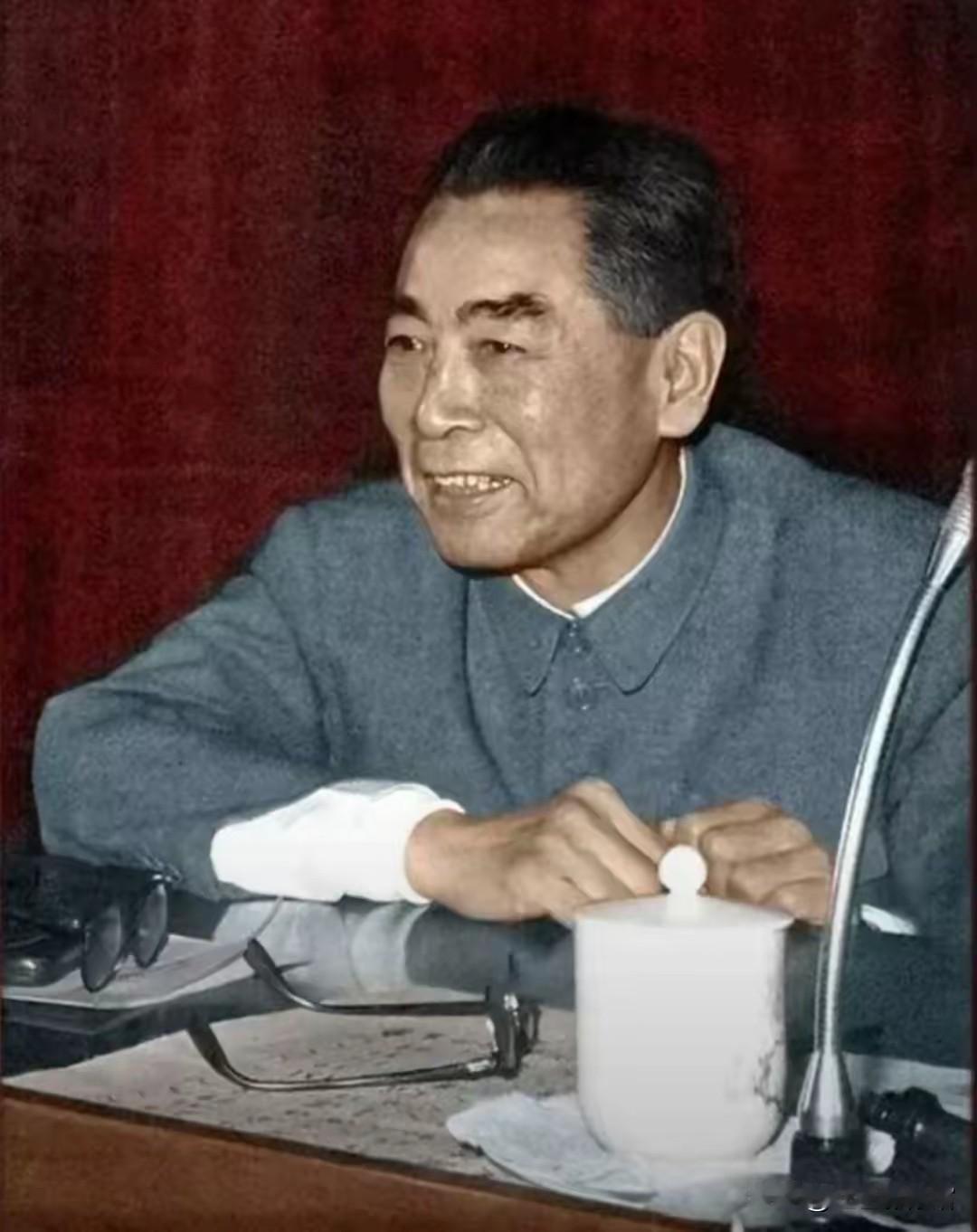 这是周恩来总理的经典工作照，他身着中山装，神态亲和，专注投入，桌上的白瓷杯与话筒