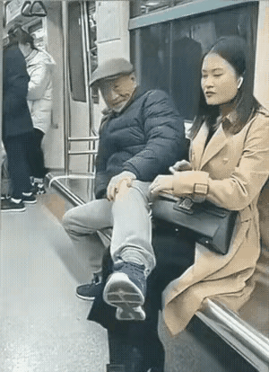 地铁上，一位大爷把腿跨在邻座美女的大腿上，大爷面对别人的摄像头竟然无耻地微笑。