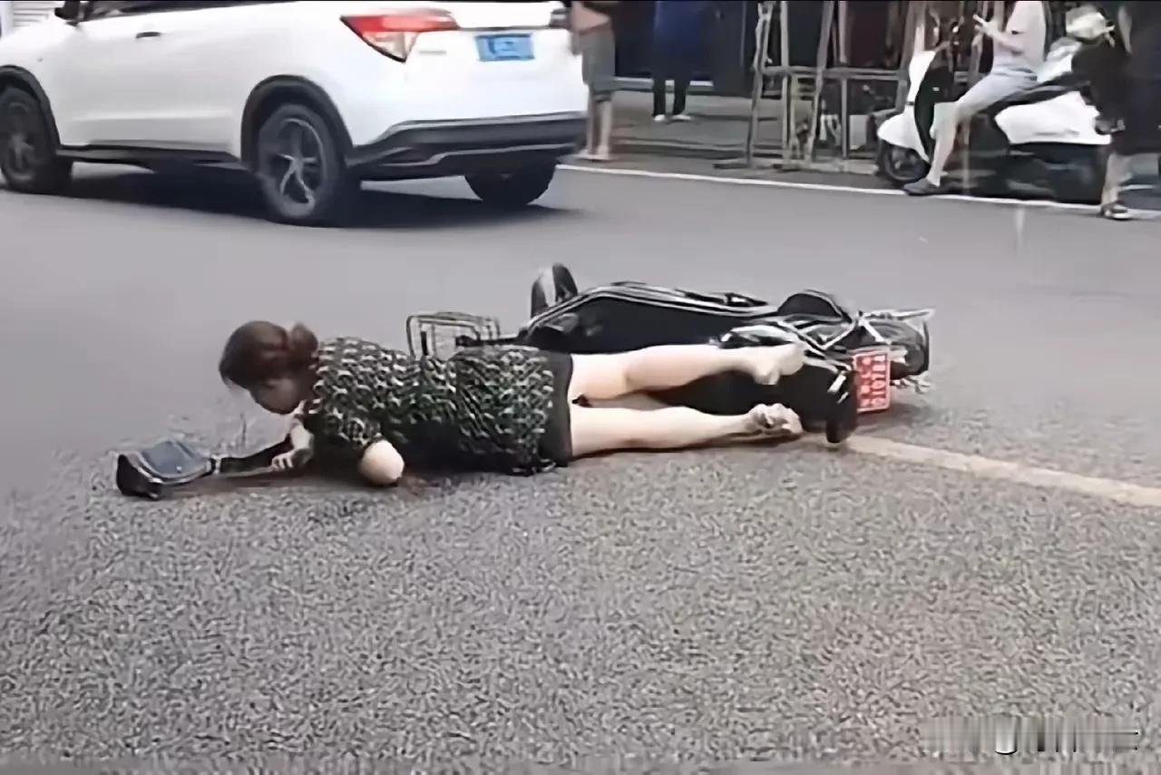 近日，四川乐山一女子骑电动车摔倒，在大街上挣扎了很久都没有爬起来，但却无人敢扶。