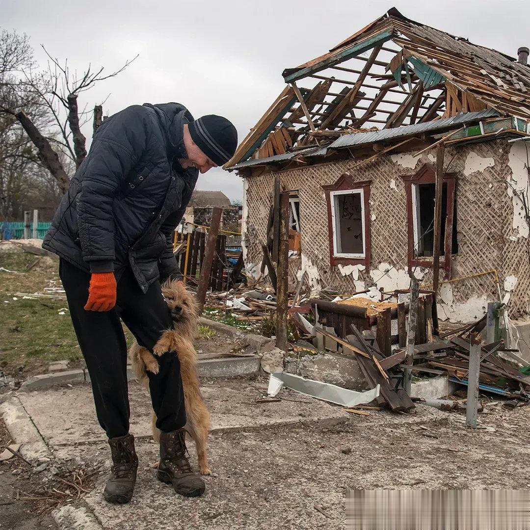 乌克兰，一只小狗在废墟前紧紧抱住一位男士的腿，久久不愿松手！