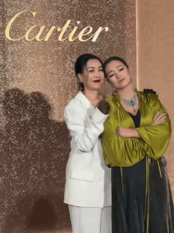 那英碰上巩俐乖多了，不但老实的让巩俐倚靠她身上拍照，还带着甜甜的笑容比手势，那个
