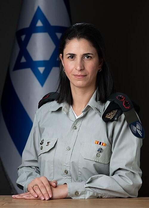 一个穆斯林家庭出身的女人，穿着以色列军装，站在特拉维夫的交接仪式上。表情严肃。