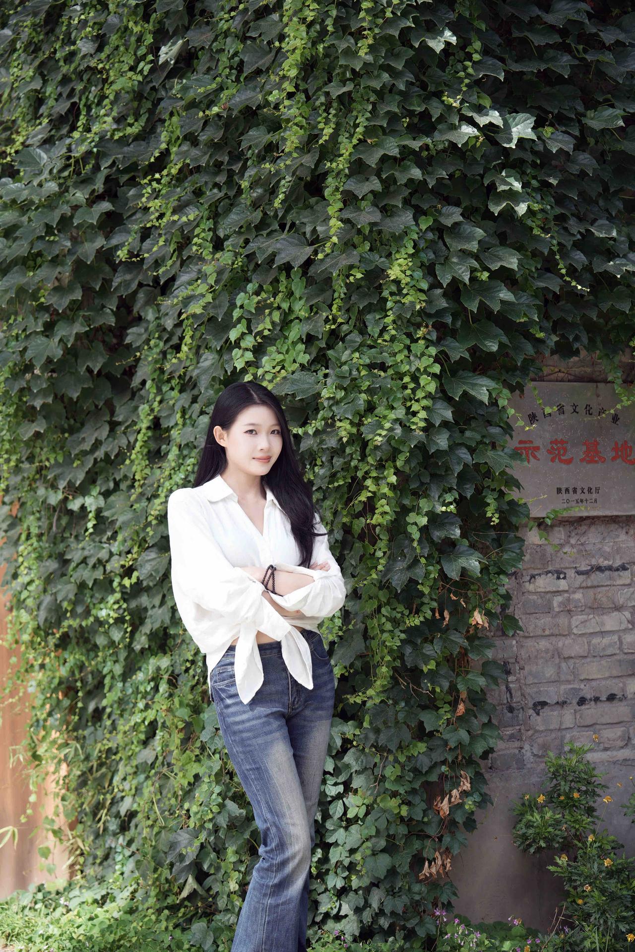 在绿意盎然的藤蔓前，优雅白衣少女，自然与时尚的完美融合。
