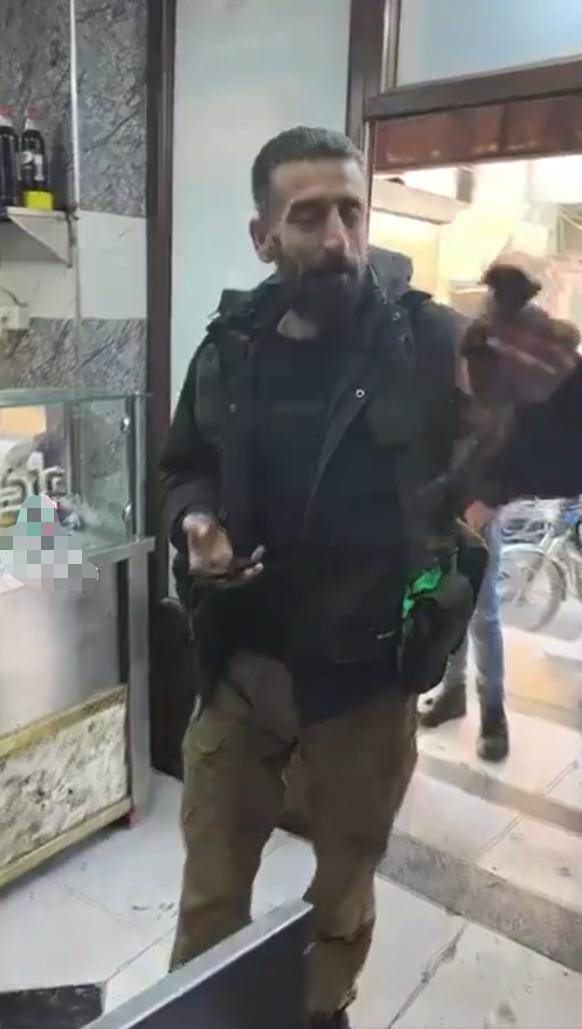 视频中一名身穿战术装备的留胡子男子在叙利亚拉卡的一家商店外展示了一截被割下的女性