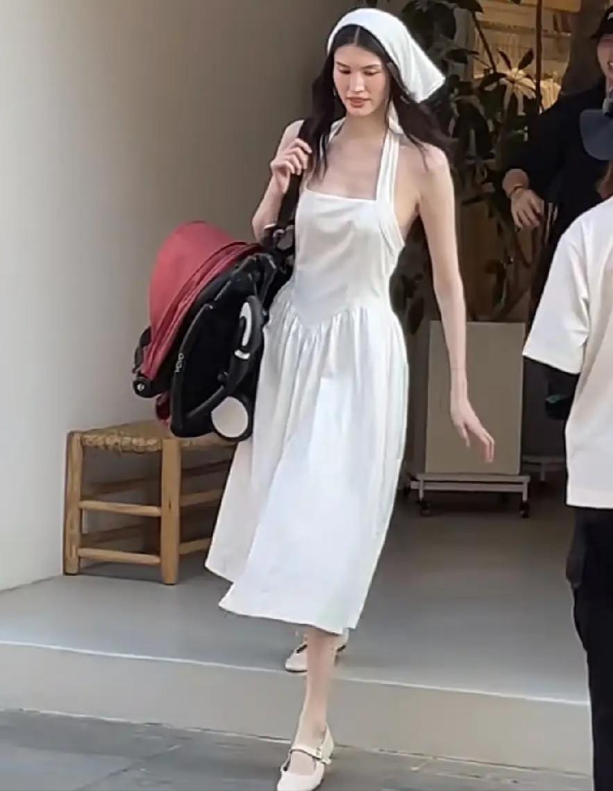 7月28日下午，何穗现身阿那亚拍摄婴儿车广告。一身白色露背长裙搭配白色头巾，推