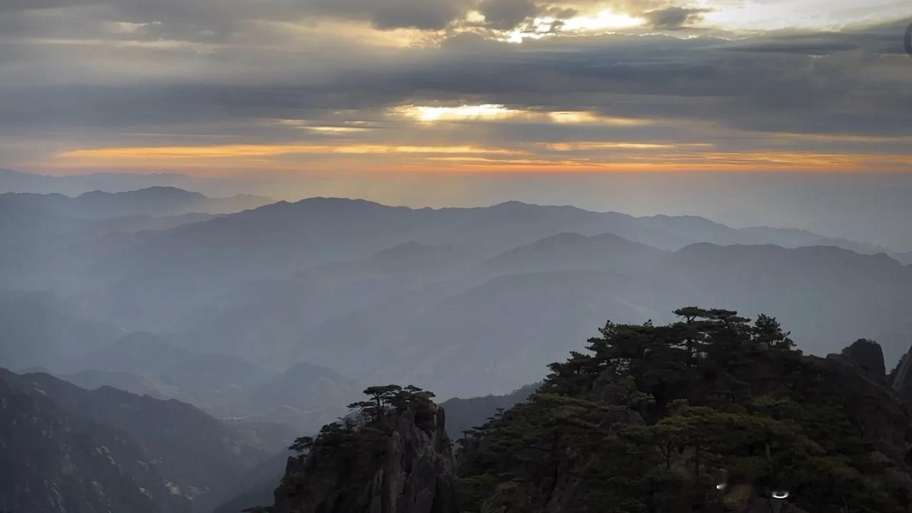 黄山日出，美不胜收！早晨的太阳不是很明显，只有霞光透过云层照射出来。站在山顶