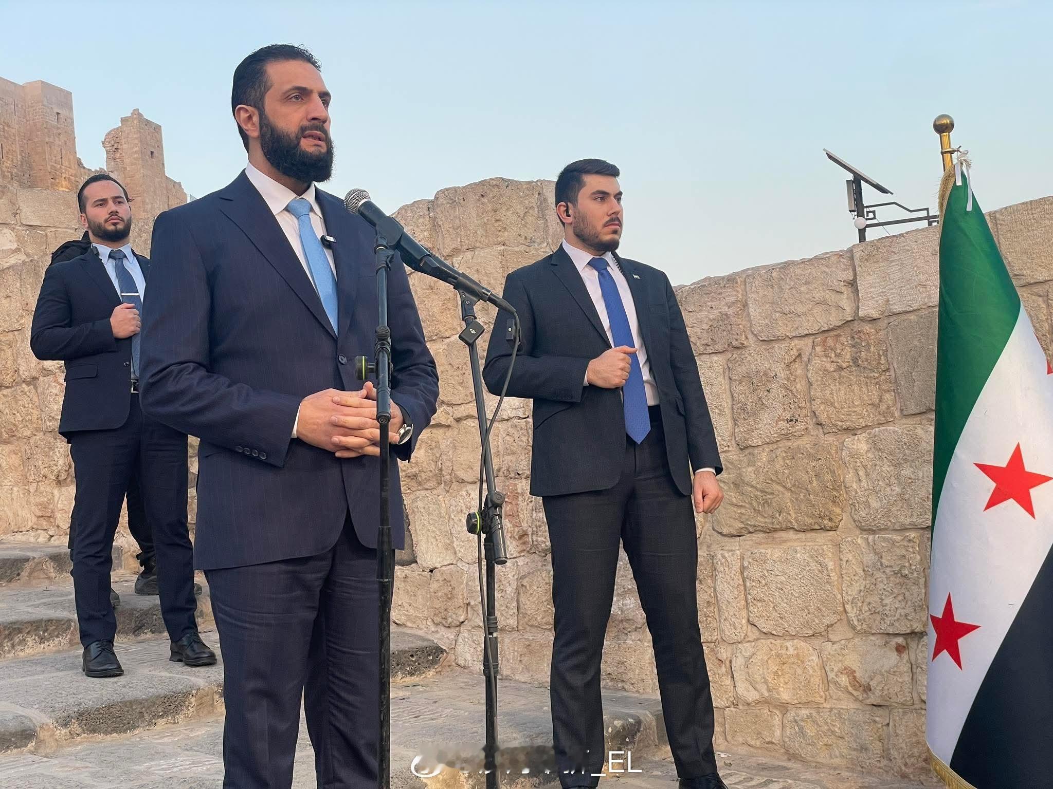 朱拉尼在阿勒颇城堡公开活动庆祝其夺取叙利亚政权一周年，旁边那个是他的保镖。相比于