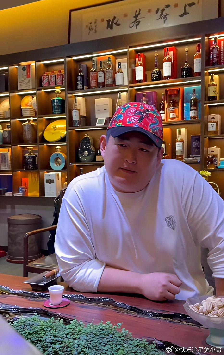 本山大叔之子赵大牛，在自家茶室酒窖做短视频时的一幕，身后酒柜摆满各类珍藏洋酒，环