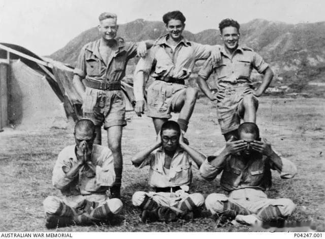 1945 年，澳大利亚皇家空军的士兵站在三名日本战俘身后，咧嘴笑着，这三名战俘被