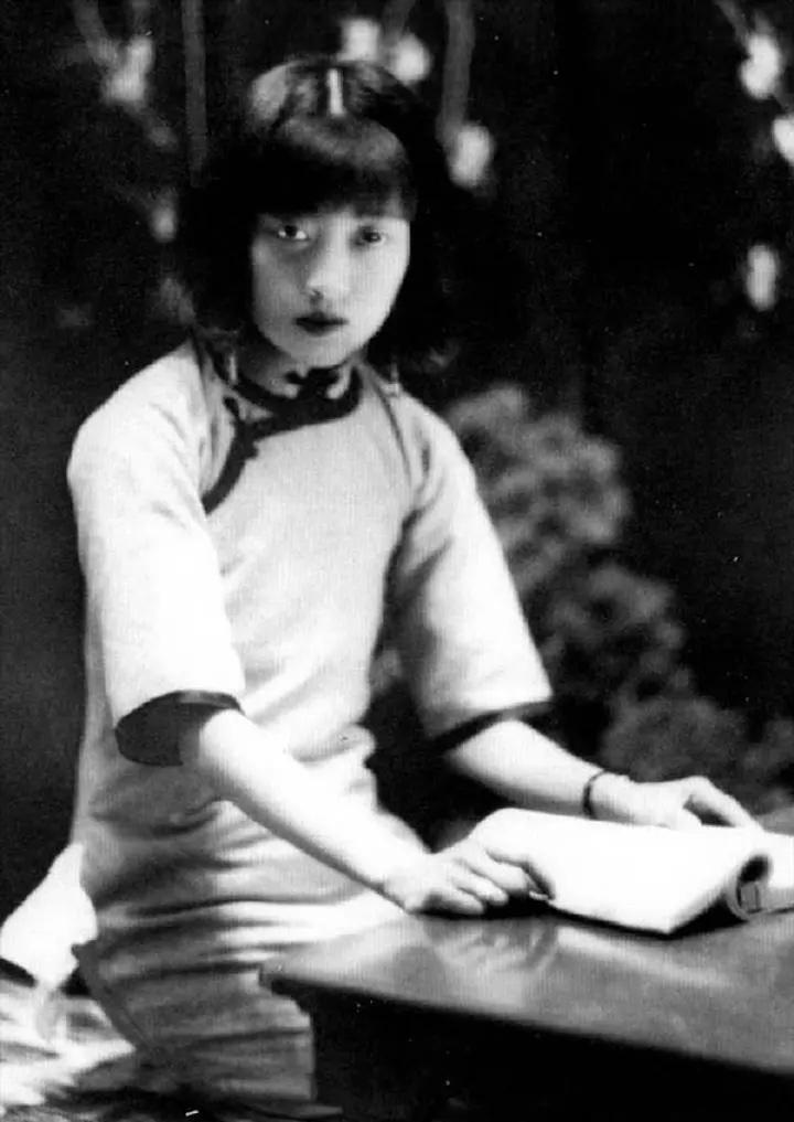 这是末代皇后婉容身穿旗袍，正在看书时的一张留影，她面容清丽，因为出身名门，从小受
