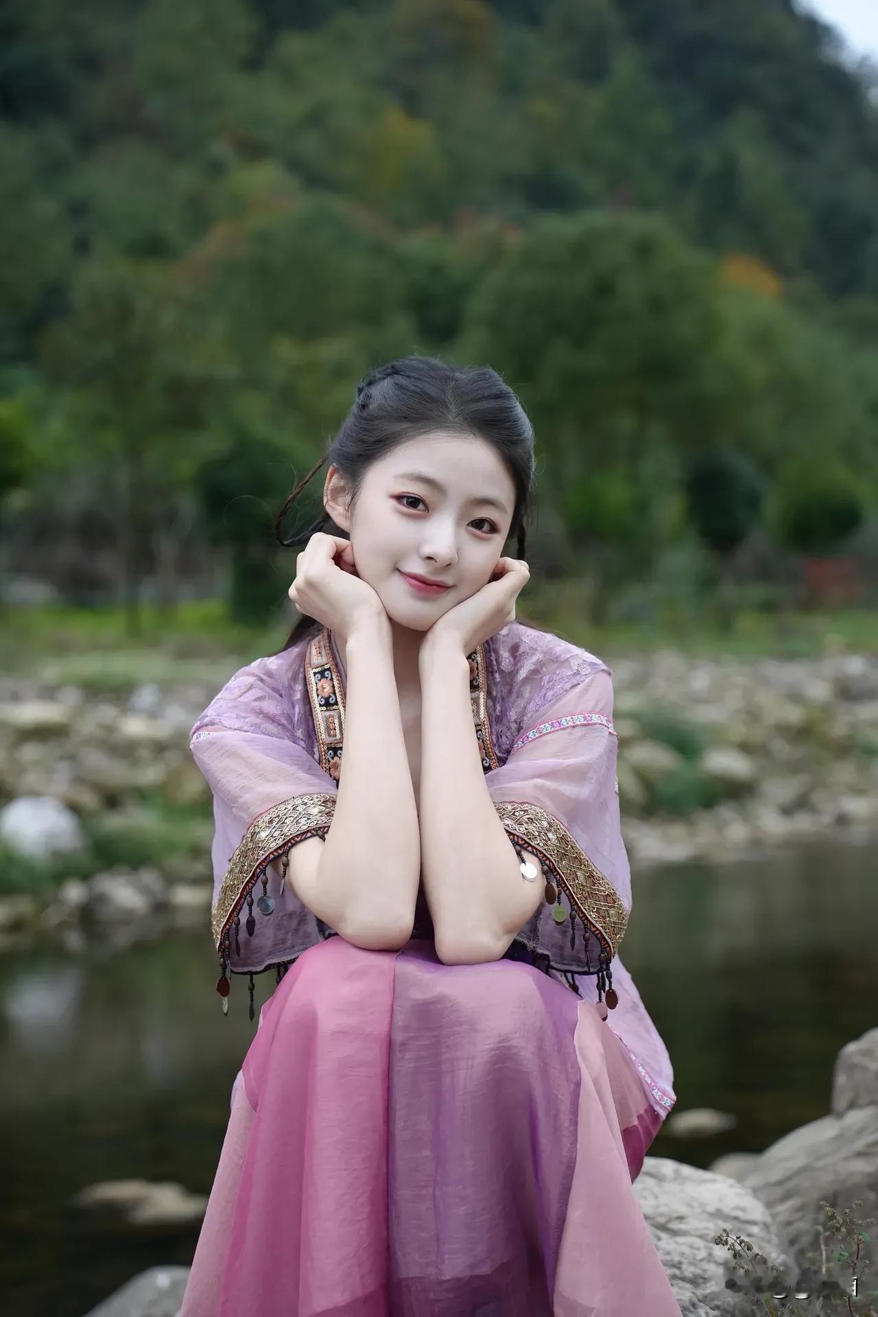 在那青山绿水的环抱中，一位古风少女身着粉裙，轻盈地伫立着，那画面美得令人惊叹。粉