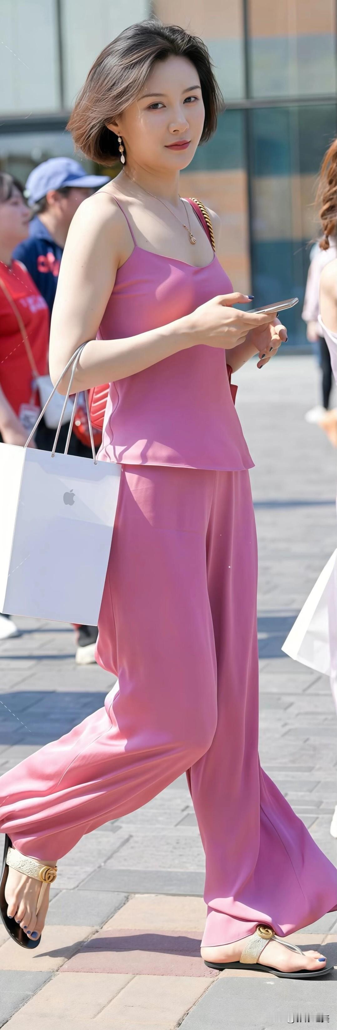 粉色吊带套装简约时尚,红色链条包与金色凉鞋点缀,气质优雅,街头购物也能尽显魅力。