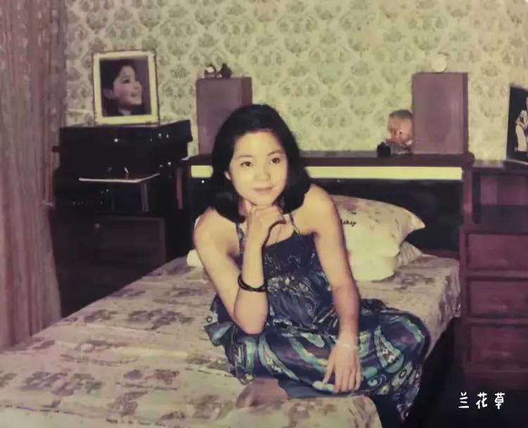 1974年，邓丽君在家中歇息。一袭深绿色休闲吊带裙，一头乌黑的发丝，右手托着下
