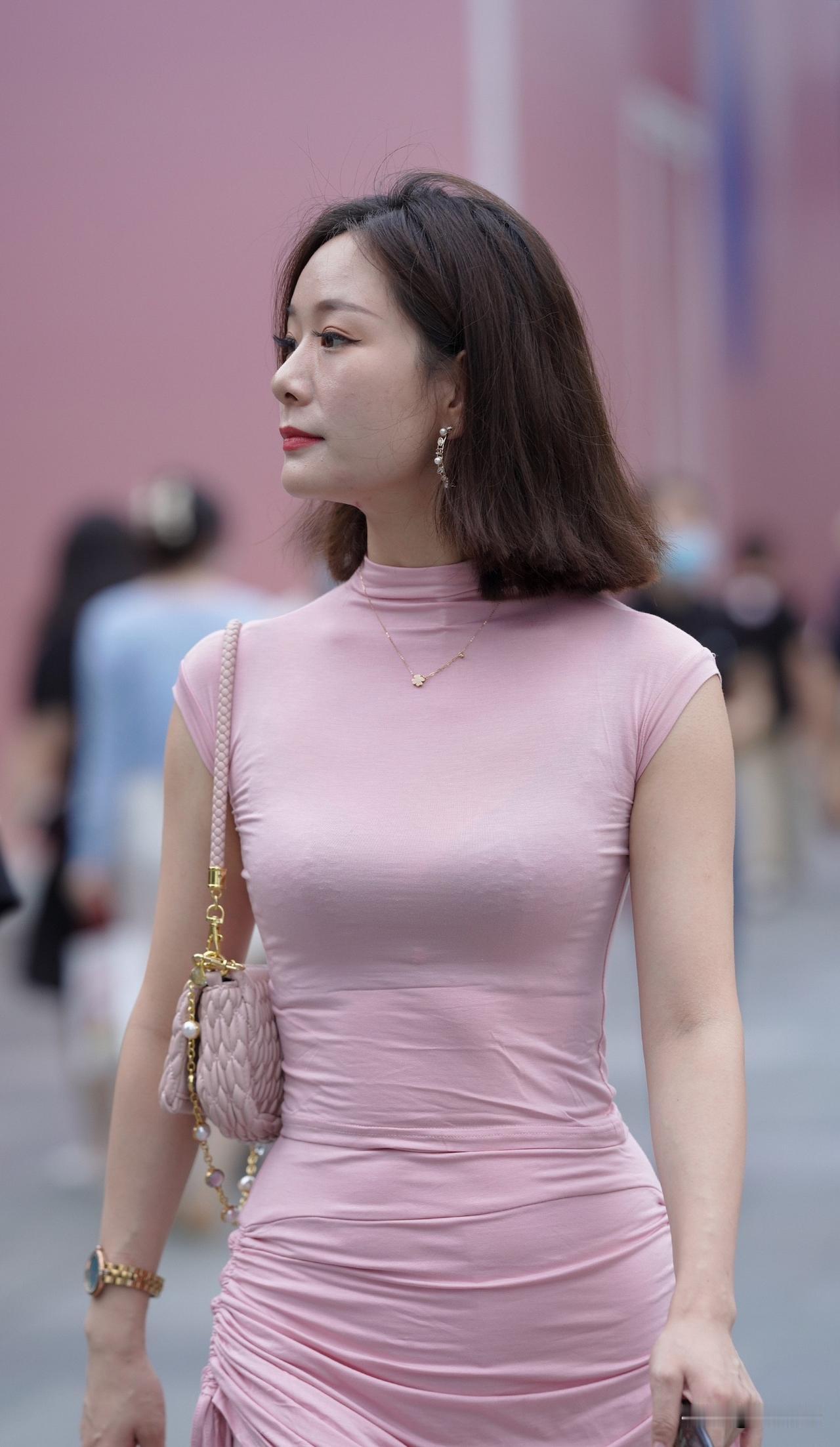 穿粉色裙子的女士在街上走着。