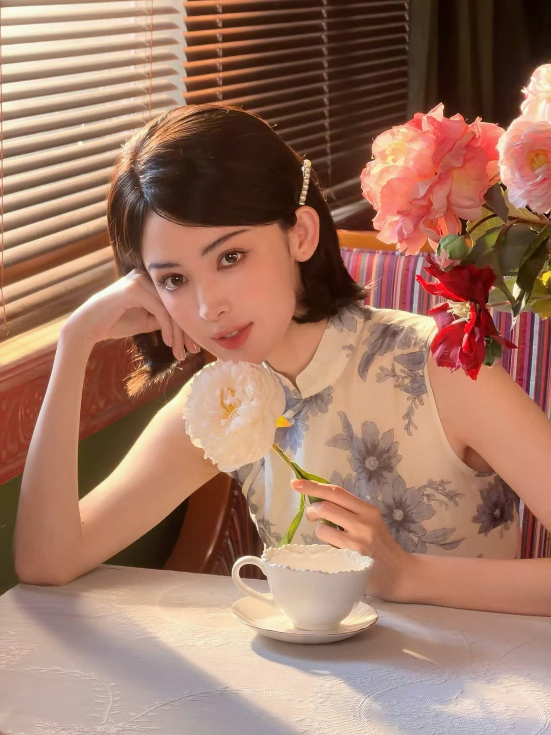 娜扎百叶窗漏进温柔光影✨娜扎身着碎花无袖旗袍，短发利落雅致，于复古