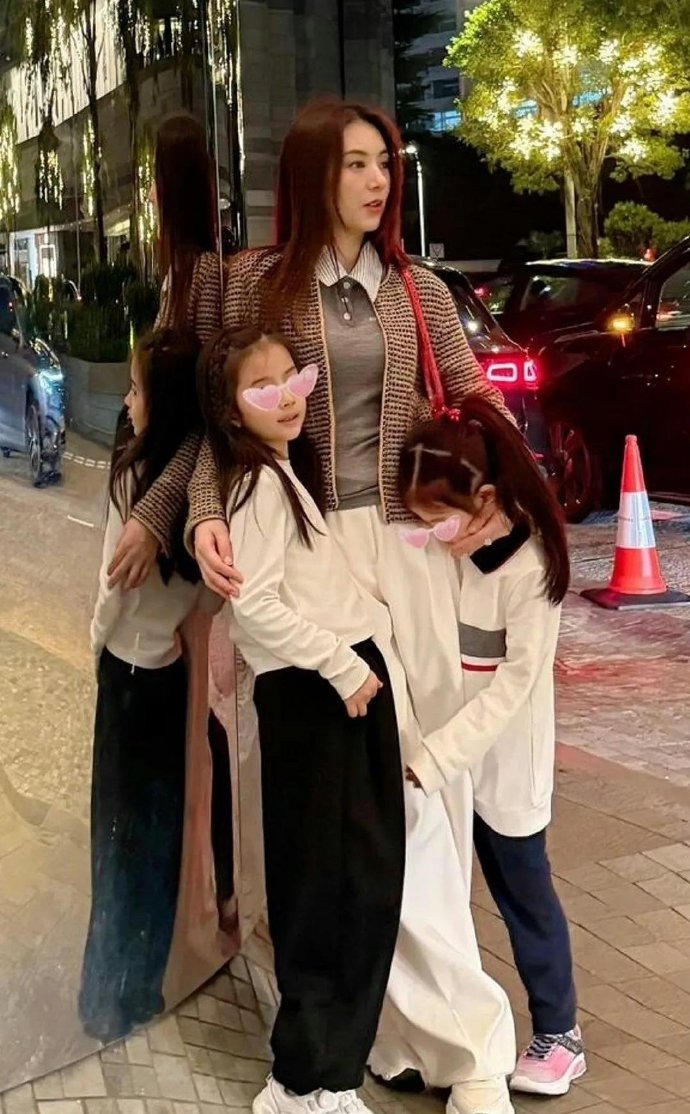 方媛带着两个女儿外出，看到有人拍摄，妹妹有点害羞，把头埋在妈妈怀里，姐姐的姿势则
