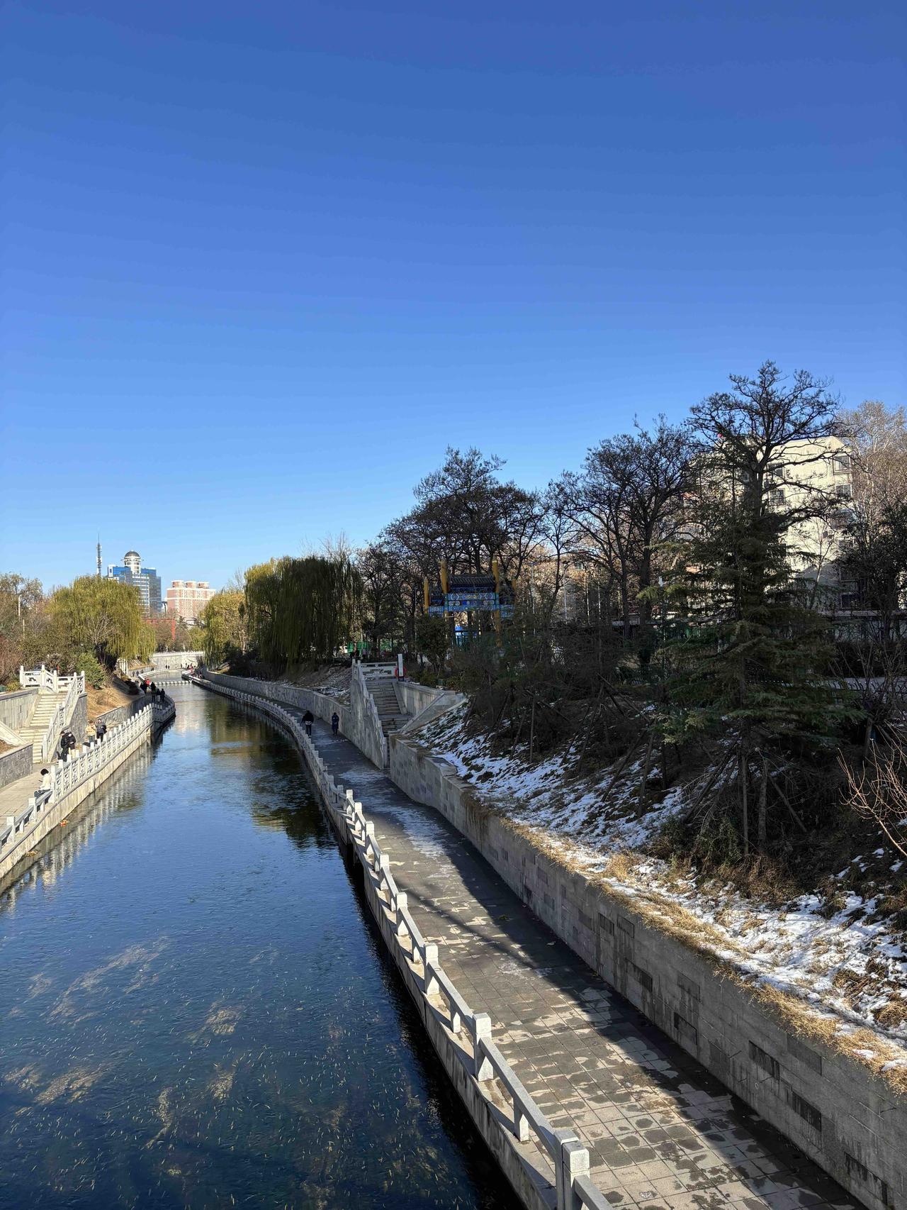 雪后的金水河，水面清透见底，残雪斑驳地覆在岸边。流水不息，与静卧的冰雪，构成了一