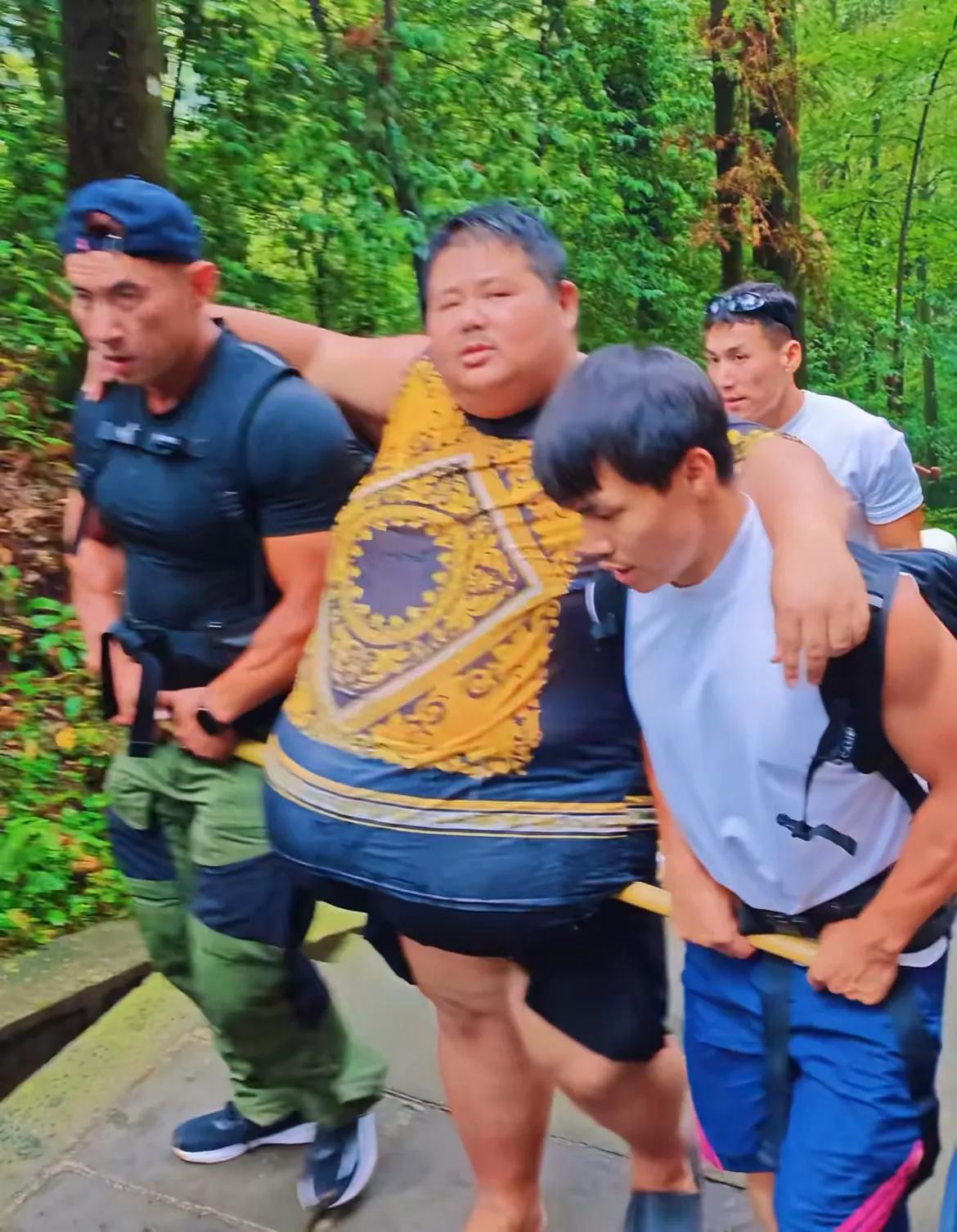 343斤网红李占良挑战爬峨眉山，肚子坠得走不动，俩同伴拿竹竿横着托住他肚子，一步