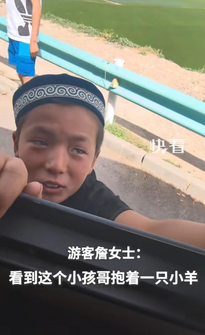 新疆，一女子自驾游时和当地小孩玩了一会儿，临上车前孩子突然把一只戴小花帽的小羊羔