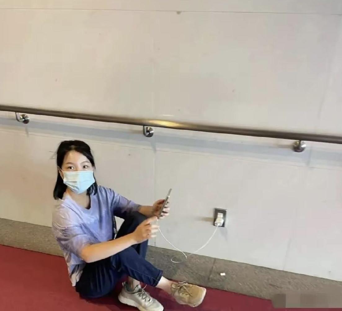 图中呈现的是一位疑似中国游客在日本旅游期间，使用公共插座为手机充电的场景被日本网