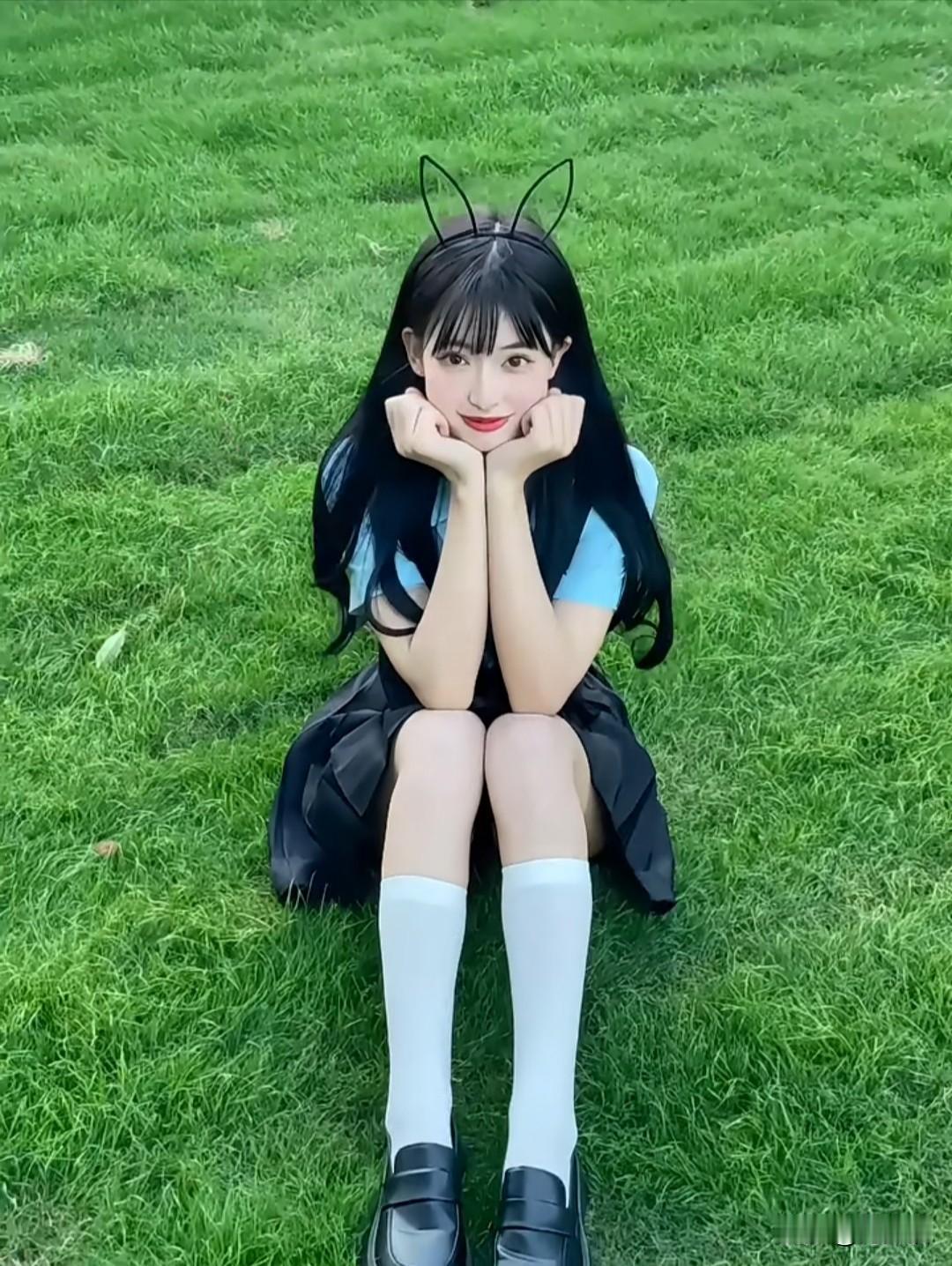 在那片葱绿的草地上，有一位戴着猫耳发箍的少女，萌态十足。她身着蓝色的衣裙，裙摆随