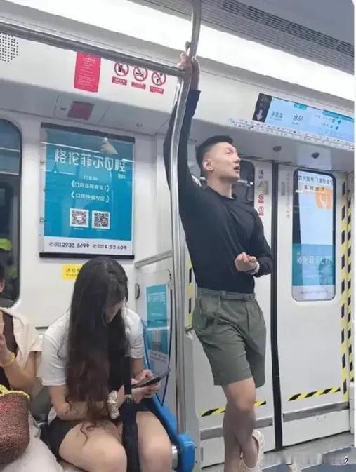 地铁上这位大哥身高臂长，但是动作看着十分妖娆，这是在摆拍吧？大热的天，上身黑色圆