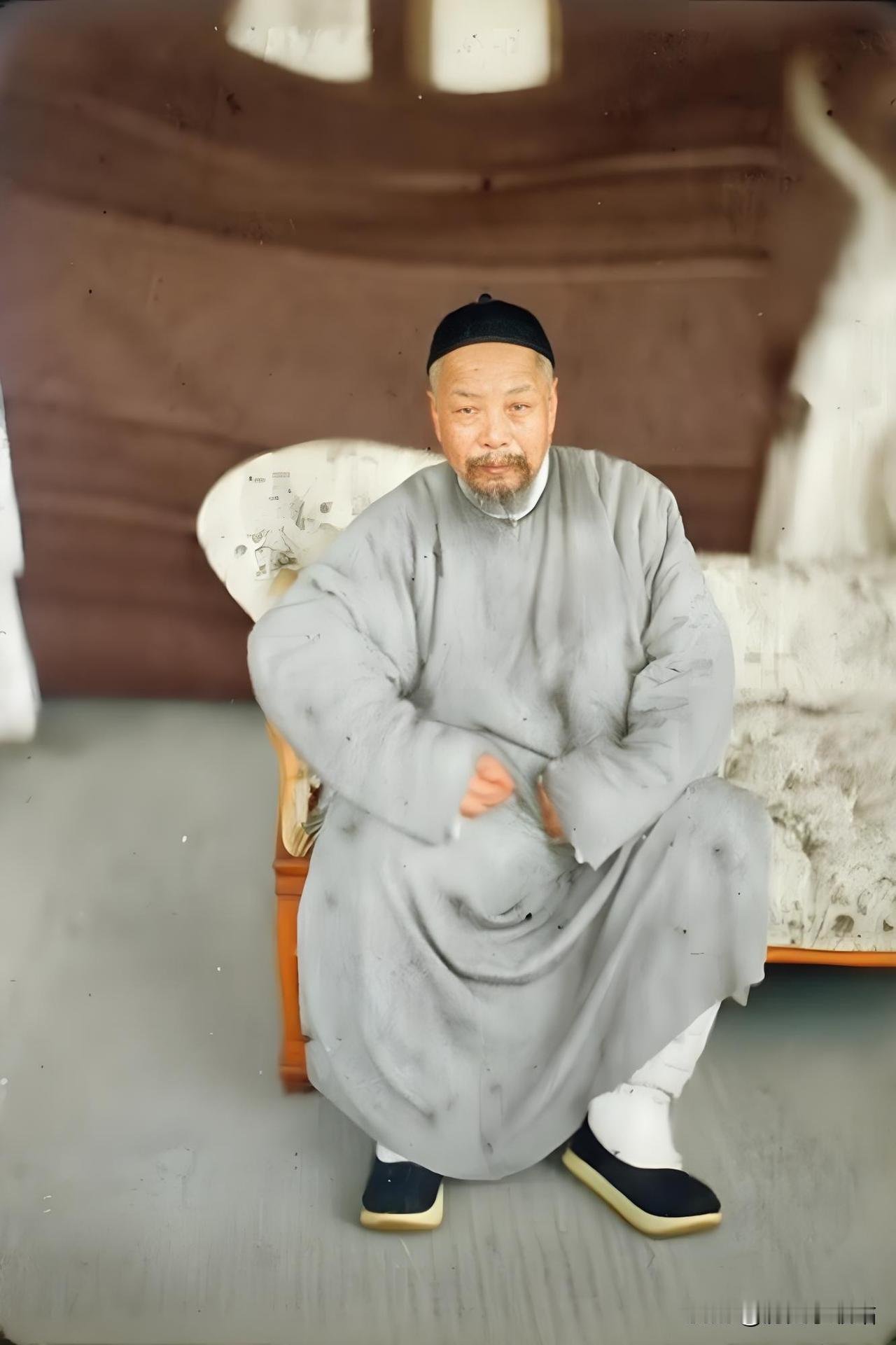 这张照片里是叶名琛被掳后的模样。他身着传统长衫，头戴小帽，盘腿坐于榻上，神态沉静