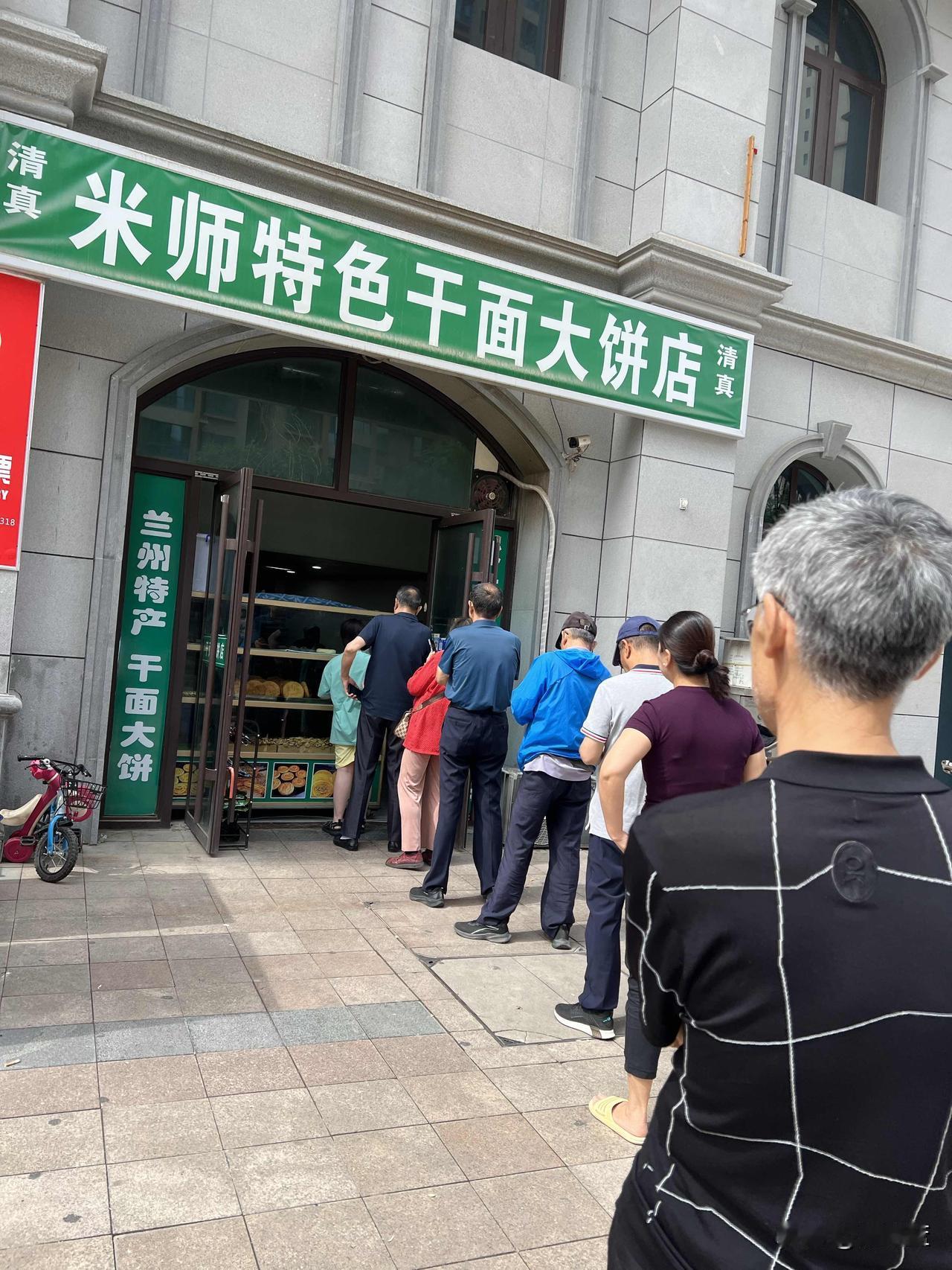 位于兰州市七里河区兰州老街商圈的米师特色干大饼店，买大饼的人就排起了长龙。前一