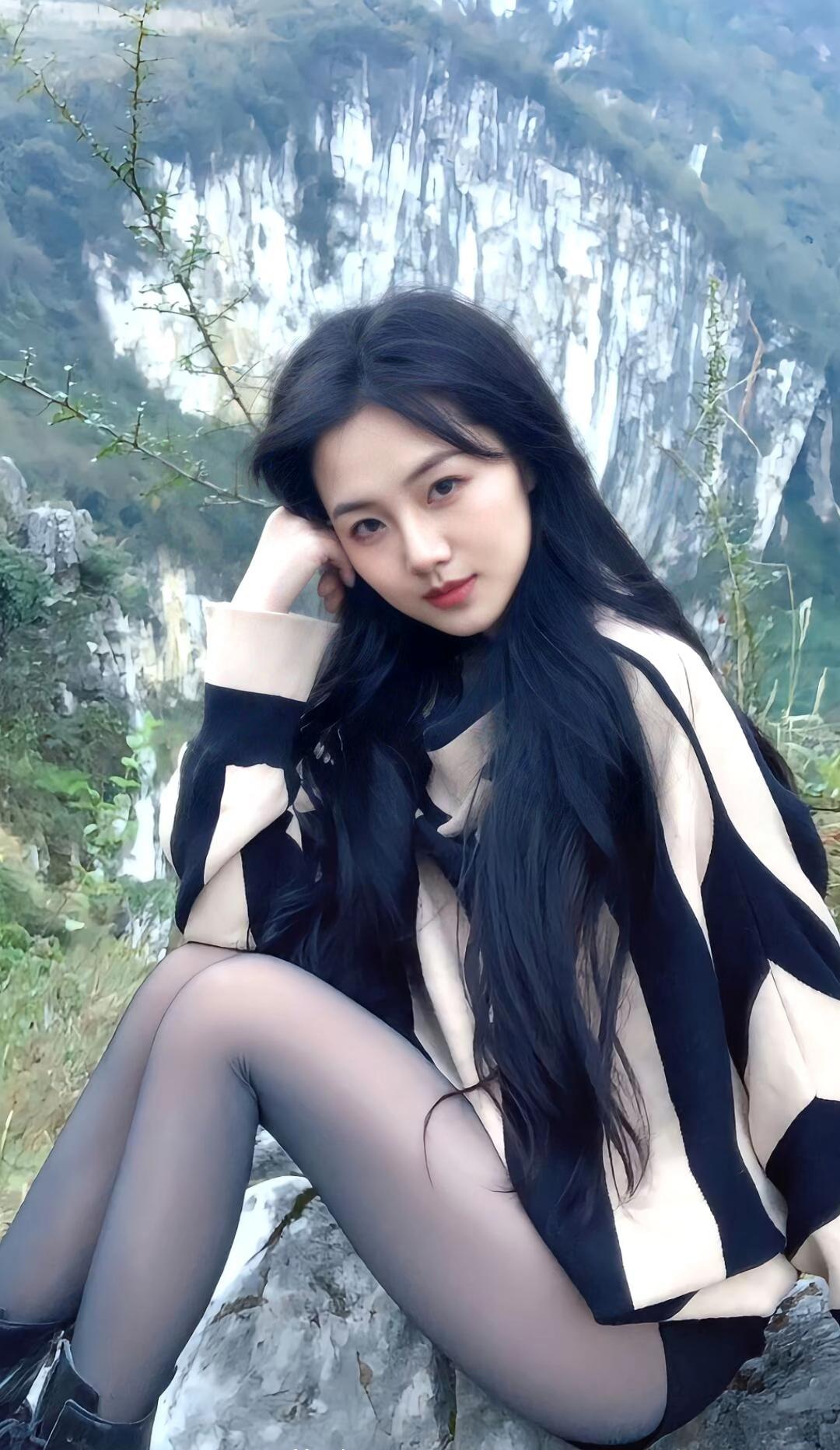 在山间岩石上，黑发少女静坐，背景是壮丽的山峰。