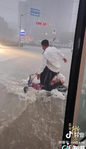 济南下了一场暴雨，街头积水。一位母亲骑车载着孩子前行，却因路面湿滑，连人带车摔倒