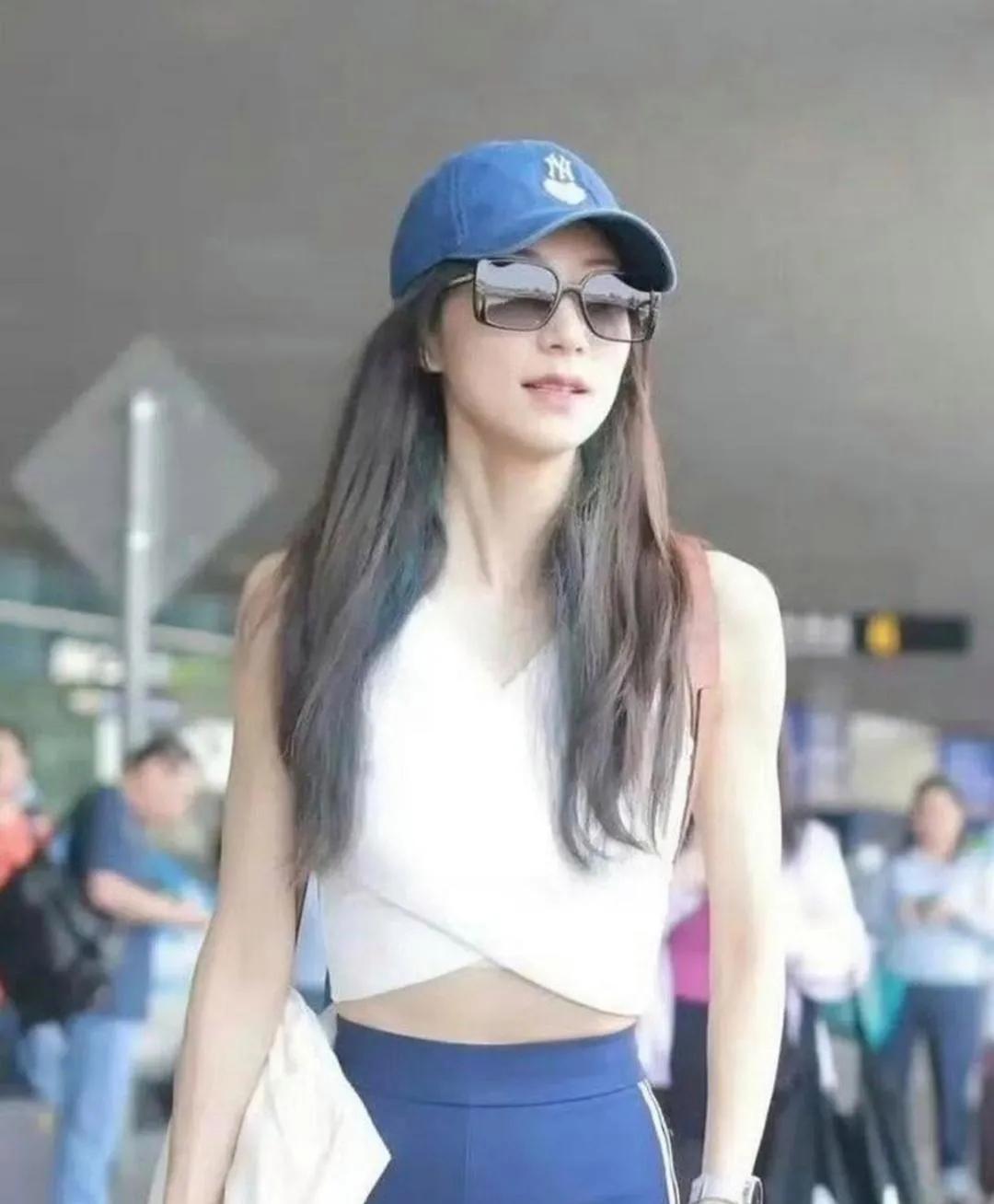 胡静这身私服太会了！交叉设计的白背心显腰细，侧边条纹运动裤拉长比例，蓝帽+白包的