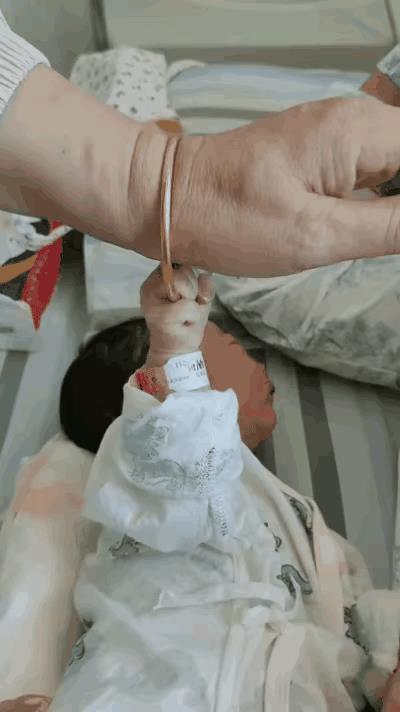 太奶奶去医院看望刚出生的重孙子，伸手刚想摸摸宝宝，就被宝宝一把攥住了戴了几十年的