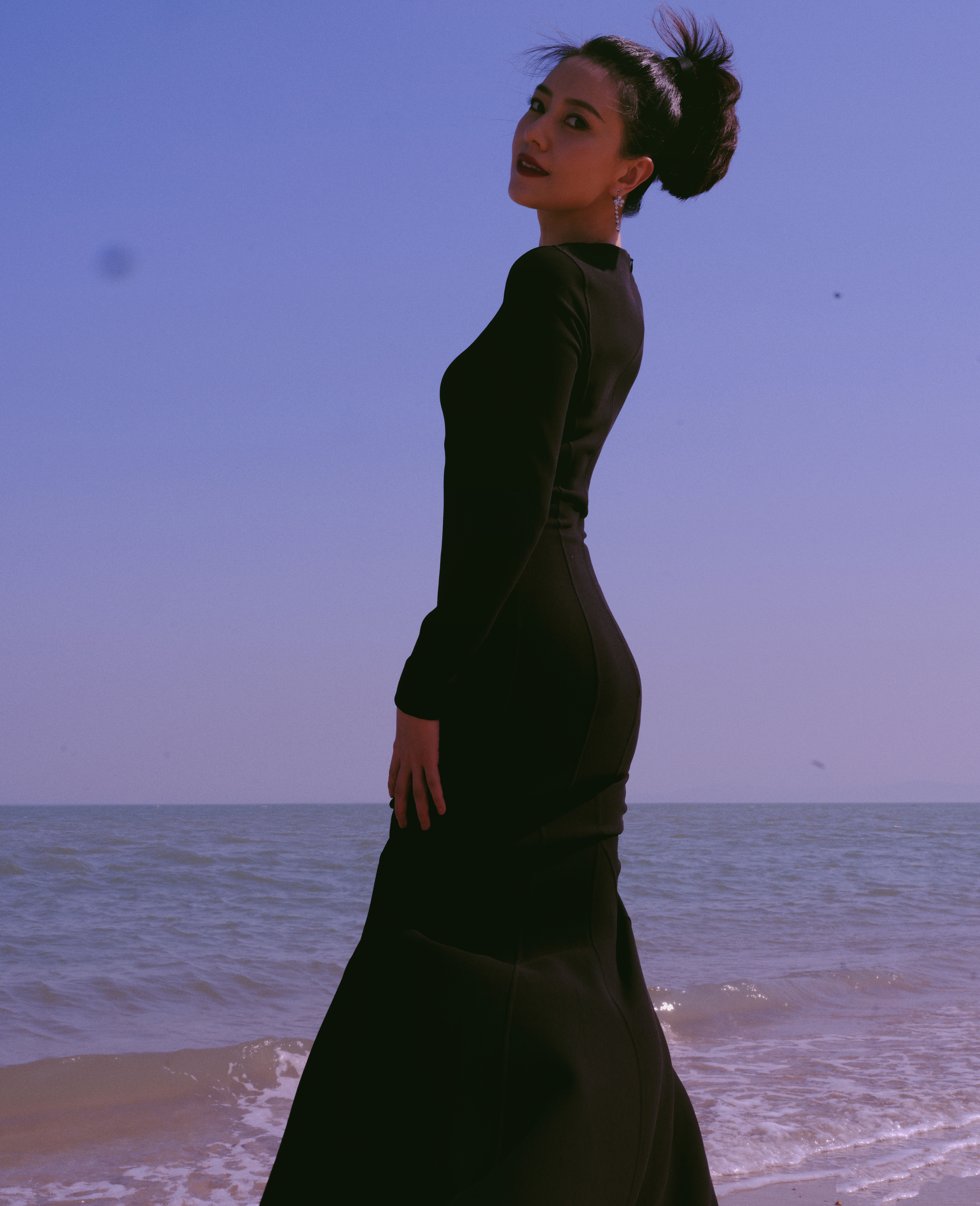 高圆圆独有的松弛与优雅展现得淋漓尽致。她身着一袭黑色修身长裙，在澄澈蓝天与蔚蓝