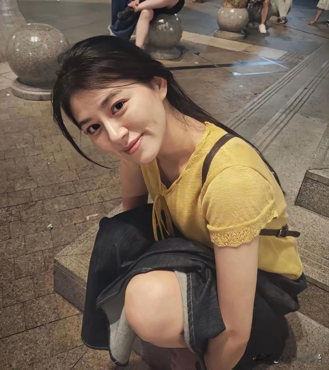 夜风吹软了街景，鹅黄衫衬得眉眼都暖乎乎的，蹲下来笑的这一刻，像把夏夜的甜都攥在了