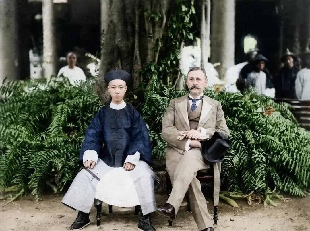 1901年，香港。18岁的载沣穿着清廷官服，坐在港督卜力旁边。卜力穿西装，拿礼帽，腿翘着。载沣的手指